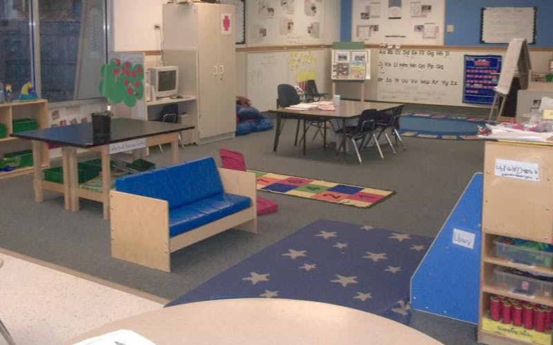 An empty classroom with multiple tables, chairs, and learning materials
