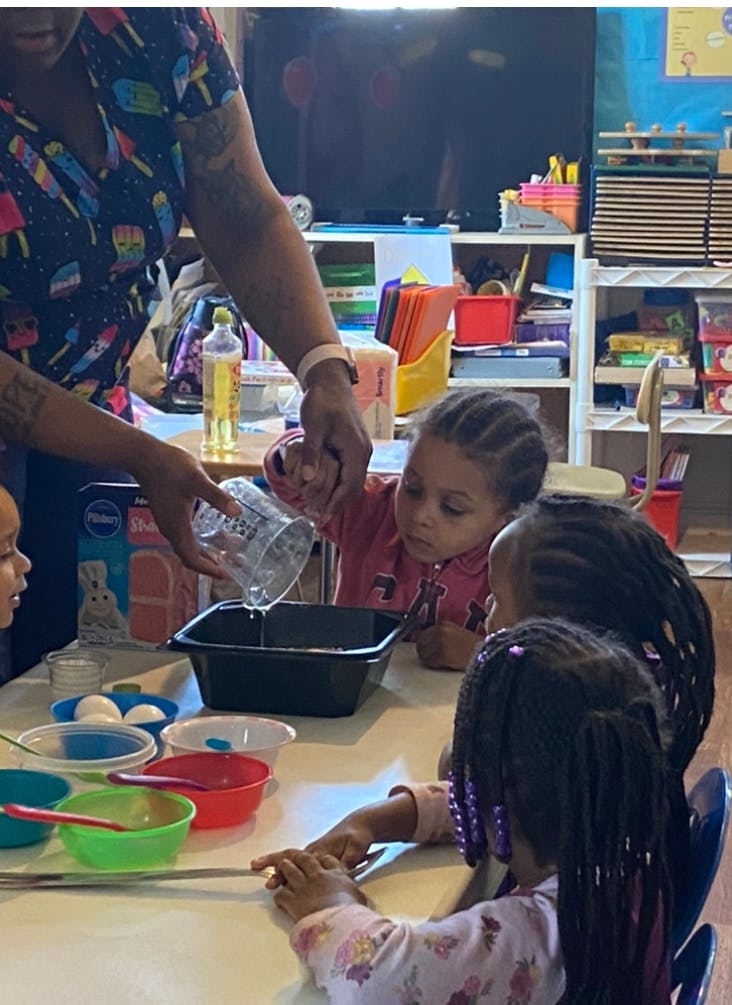 Person pouring liquid into a container with children watching