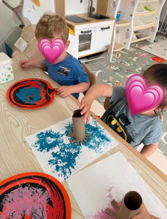 Children painting with cardboard tubes at a table