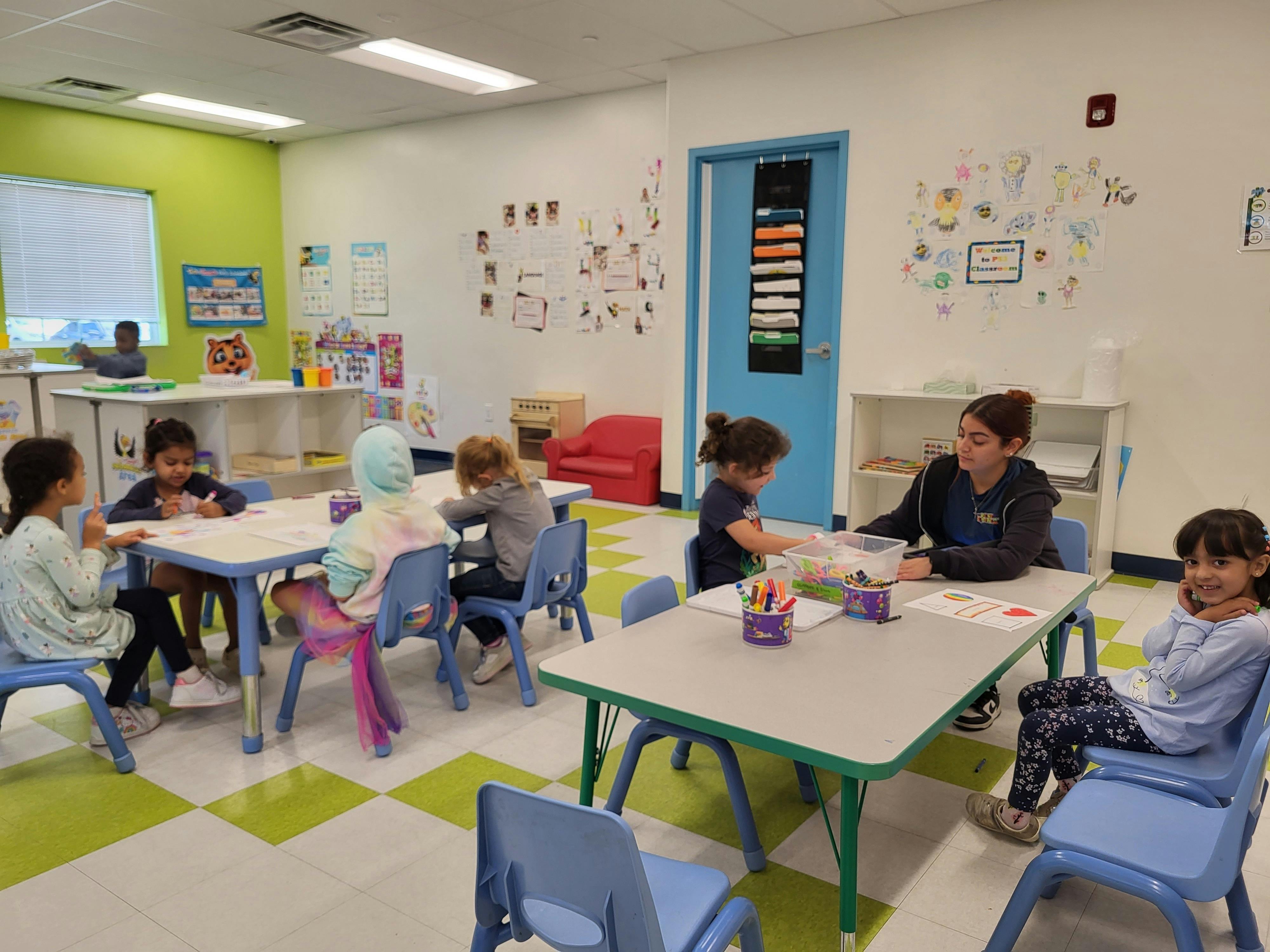 Adult and children at tables in a classroom