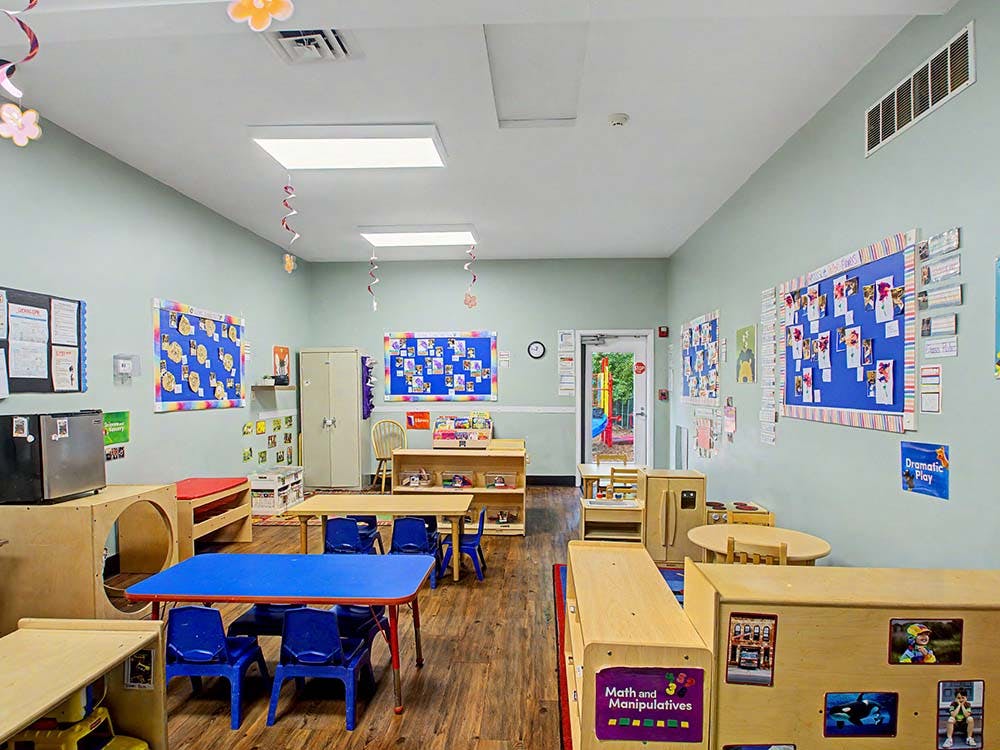 An empty classroom with tables and chairs, and bulletin boards on the walls