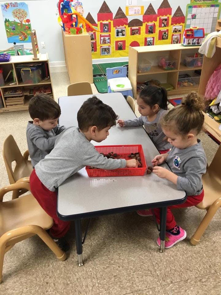 Four children at a table playing with items in a red basket