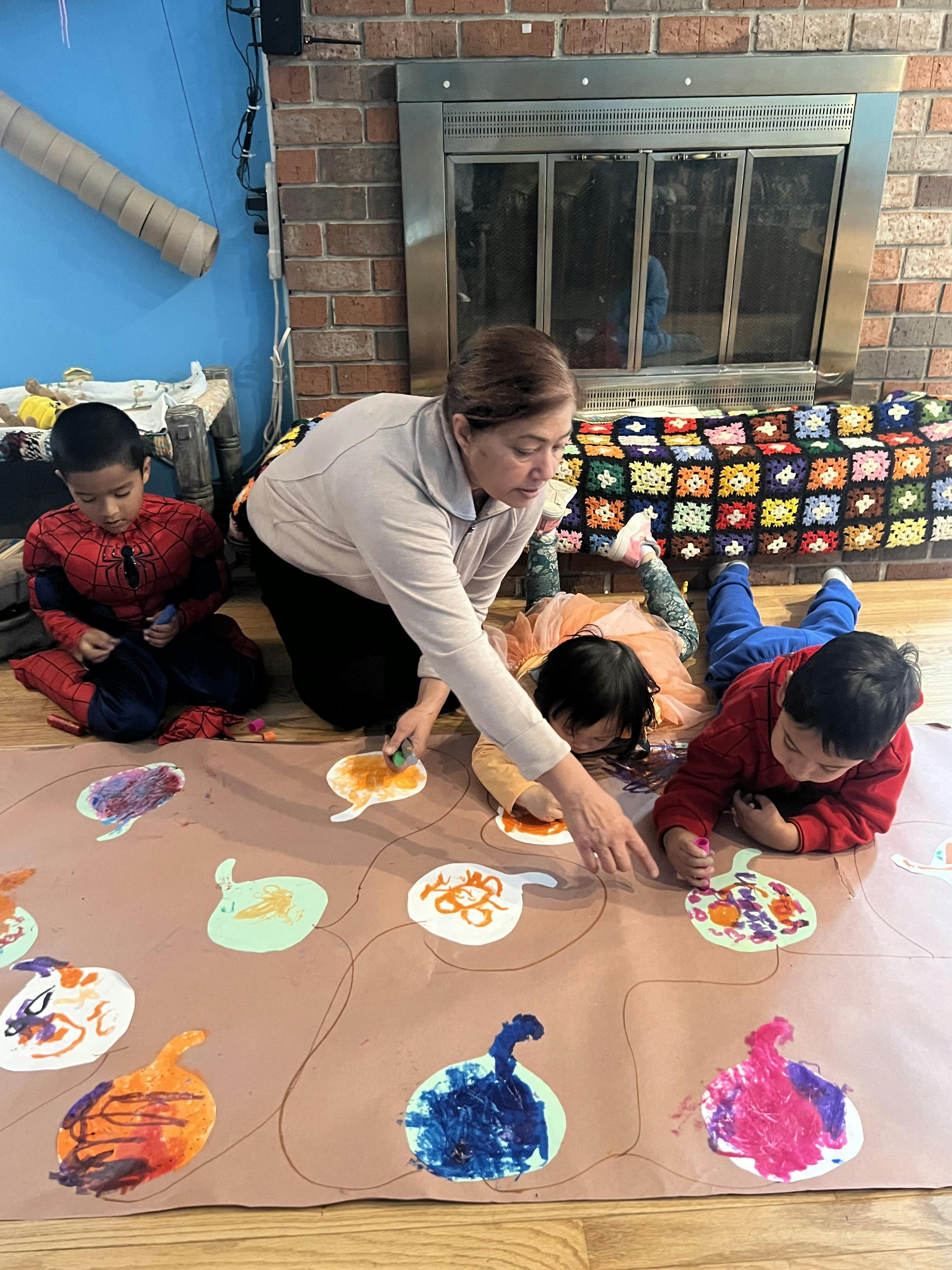Adult and children drawing on large paper on the floor