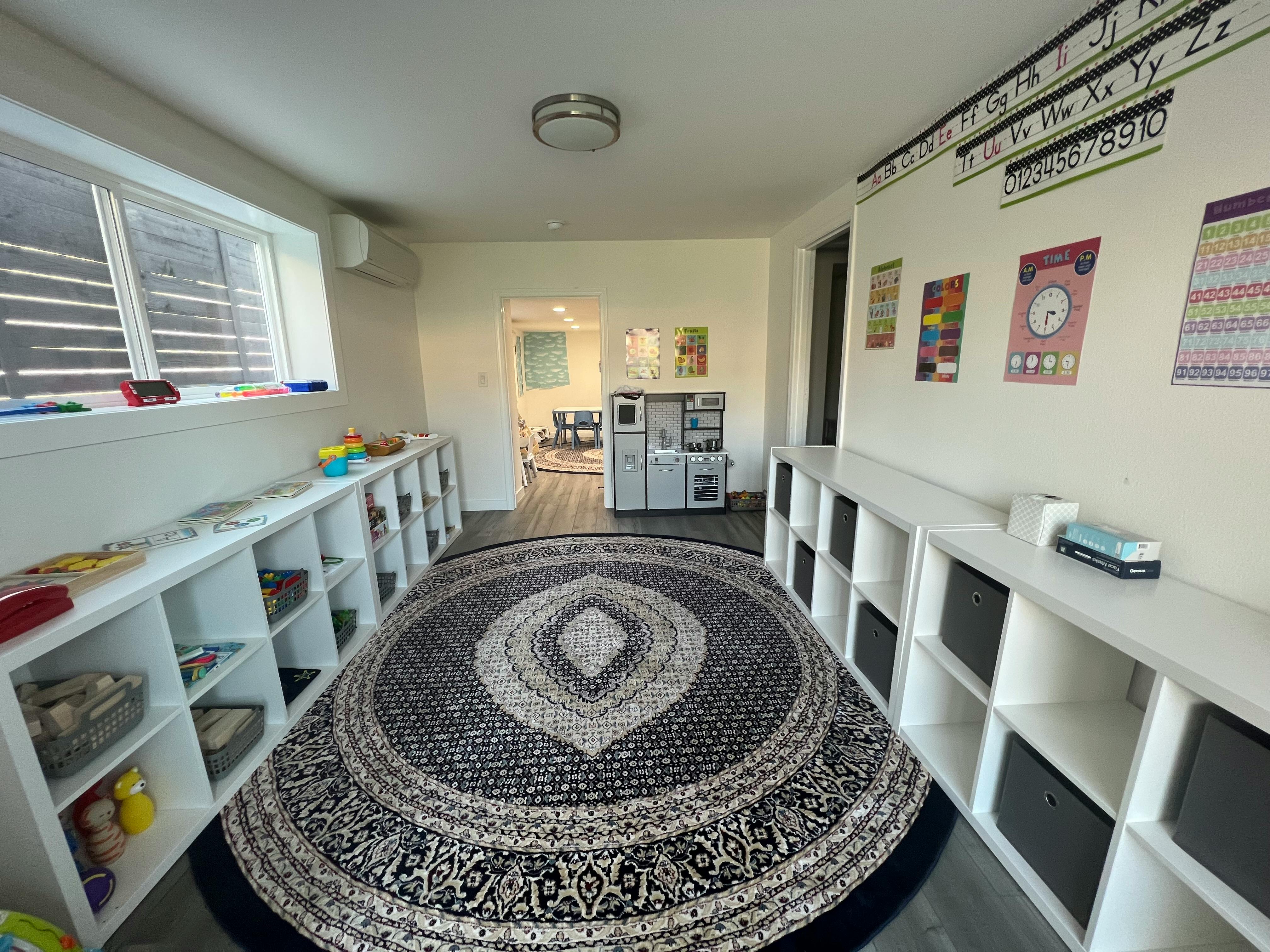 Classroom with a round rug, shelves, and educational posters