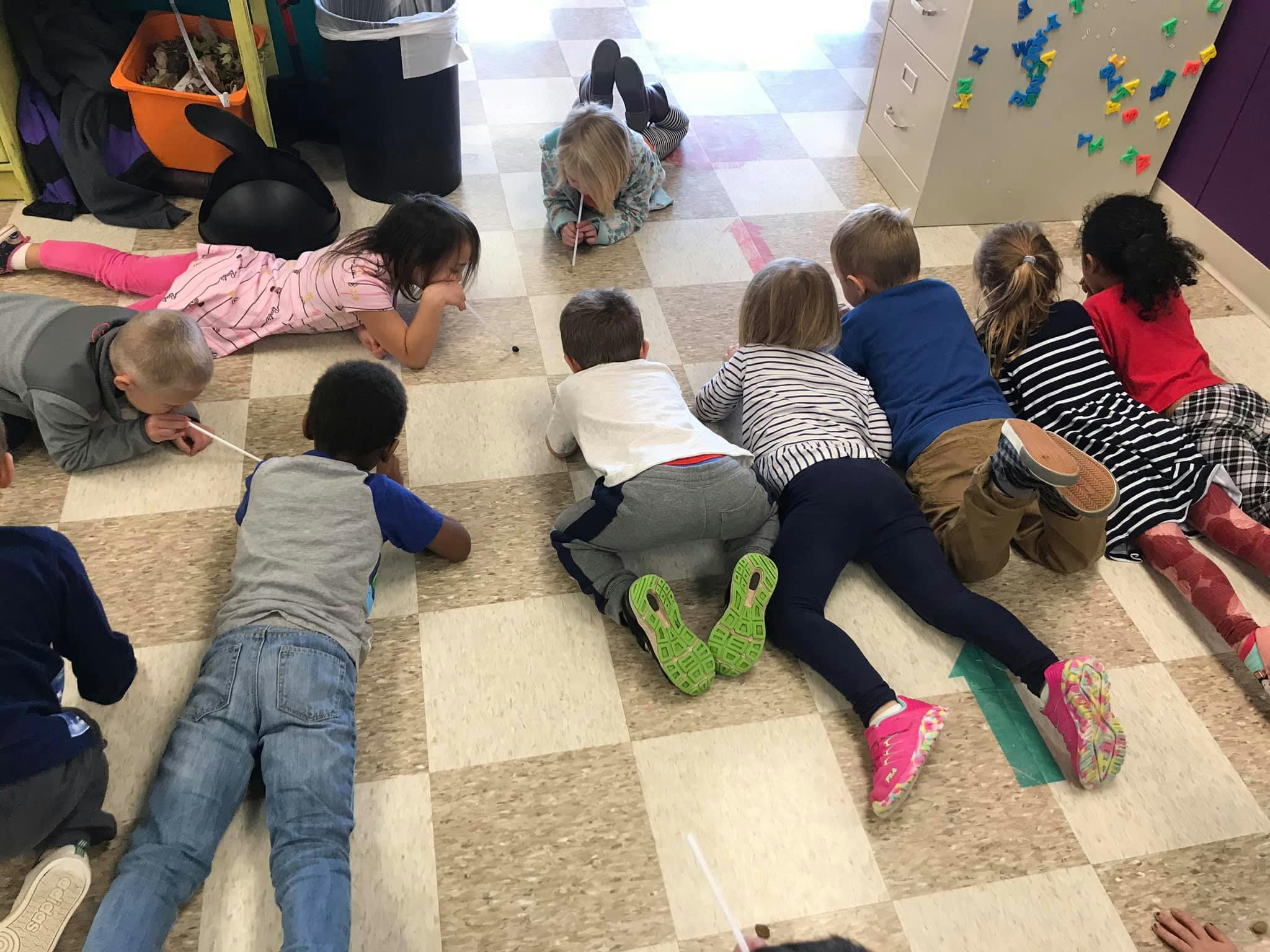 Children lying on a checkered floor, looking at something on the ground