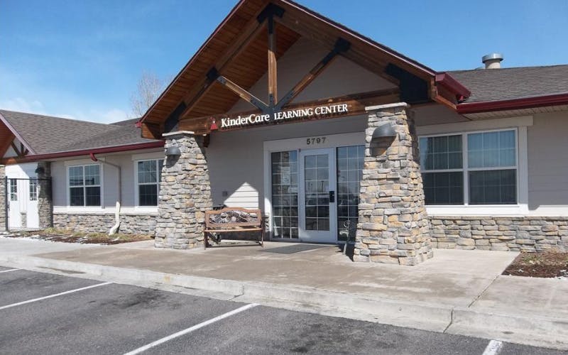 KinderCare Learning Center building entrance with stone columns and a wooden bench
