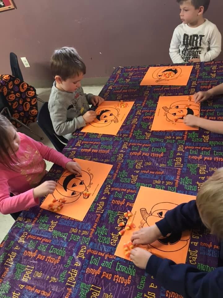 Children decorating pumpkin drawings with candy corn