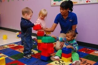 Adult and three children playing with large building blocks