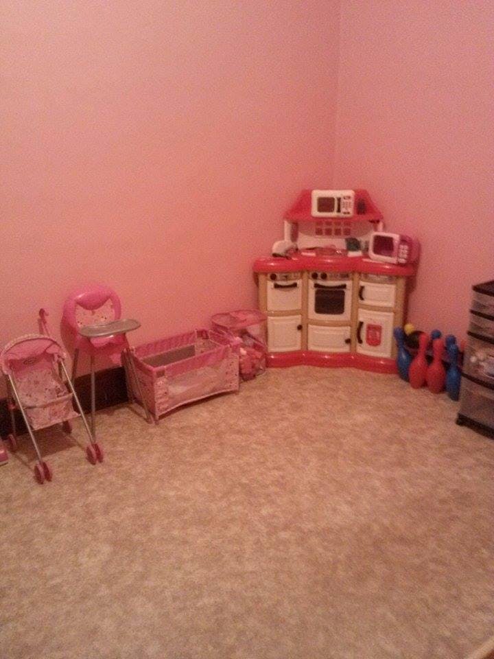 Play kitchen, doll stroller, and doll crib in a room