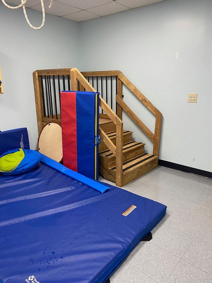 Wooden stairs with handrails next to blue and red mats
