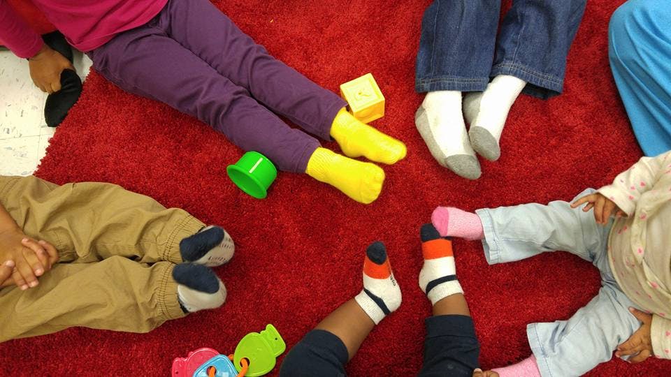 Children sitting on a red rug with toys