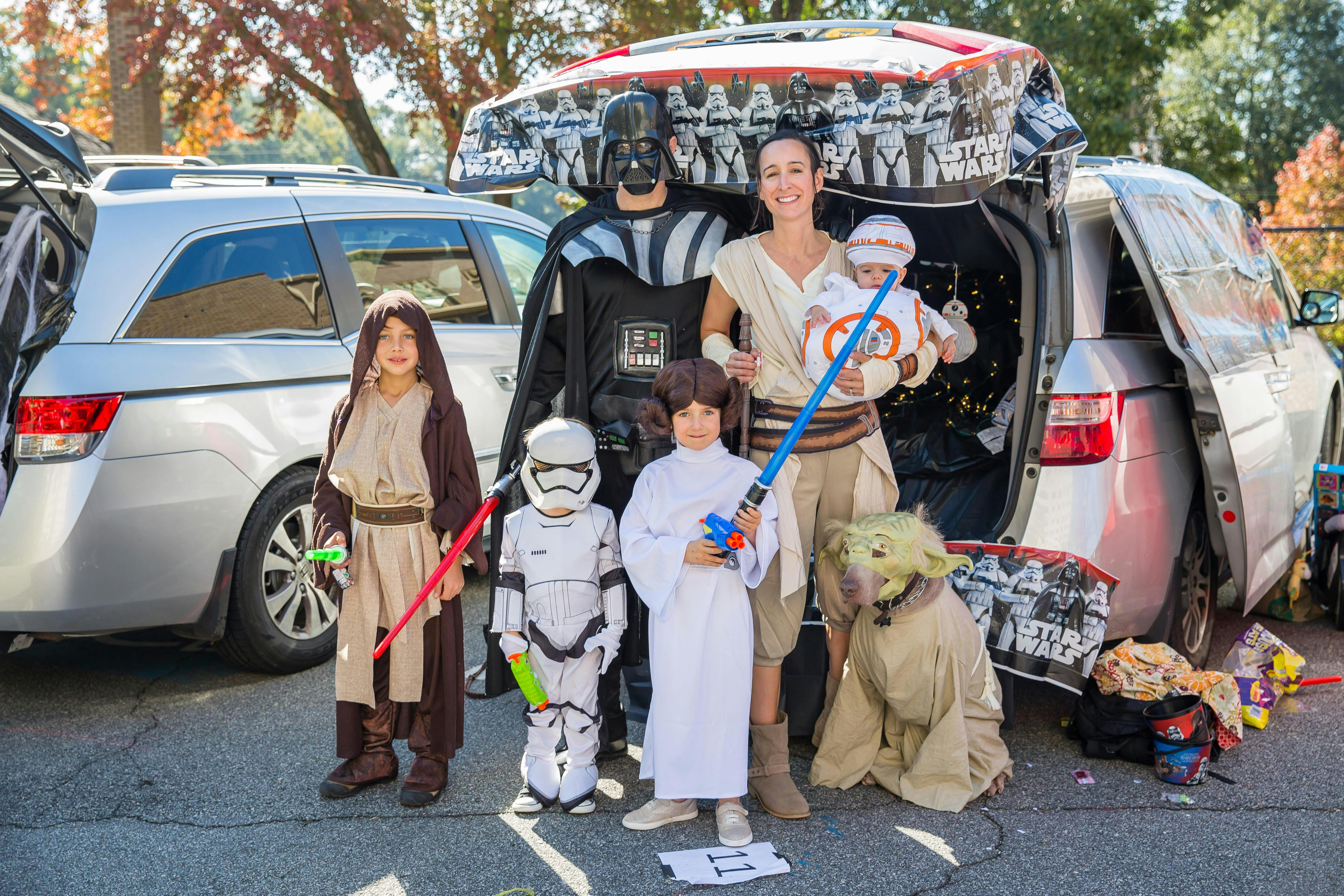 People and children in Star Wars costumes next to decorated cars