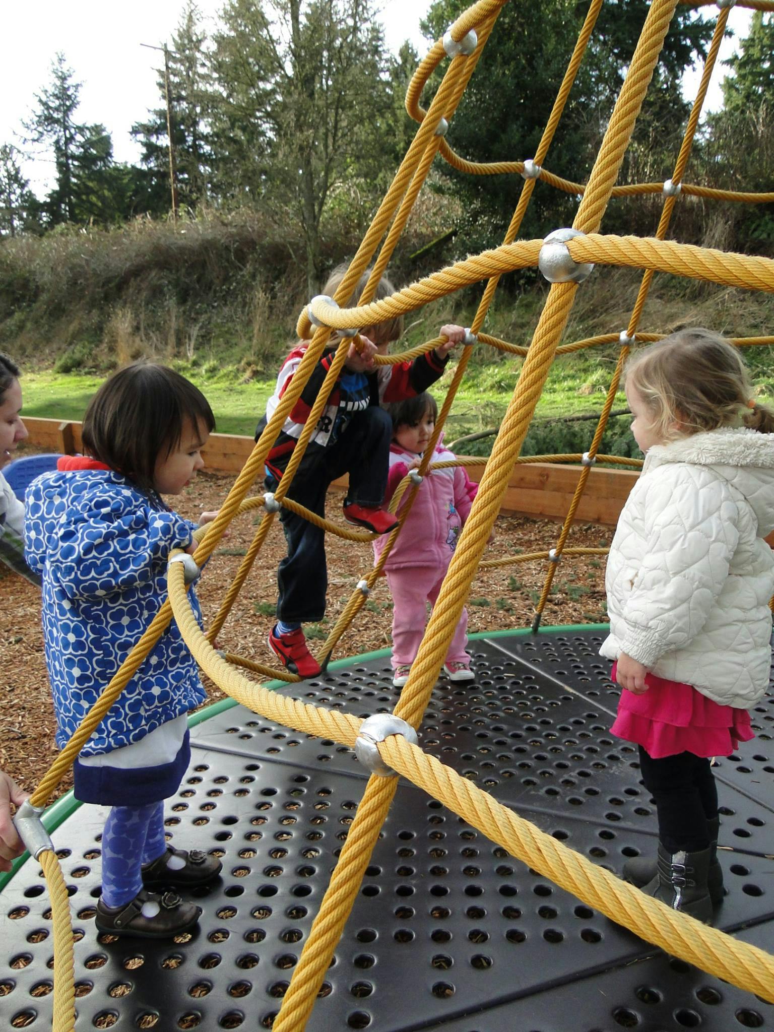 Children playing on a rope climbing structure in a playground