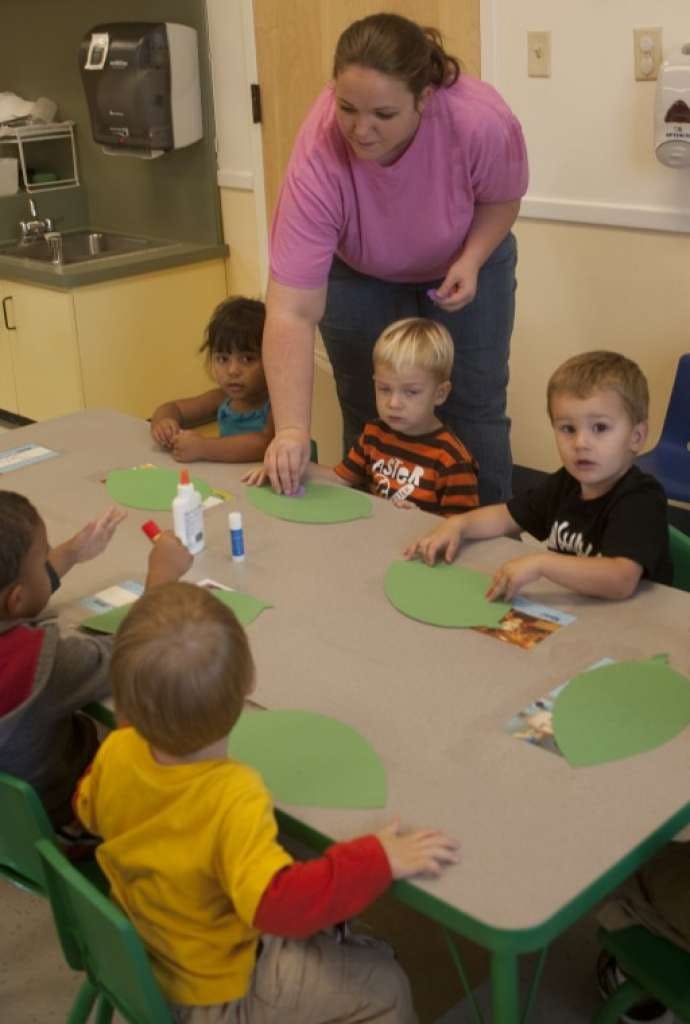 Adult and children at a table with green paper cutouts