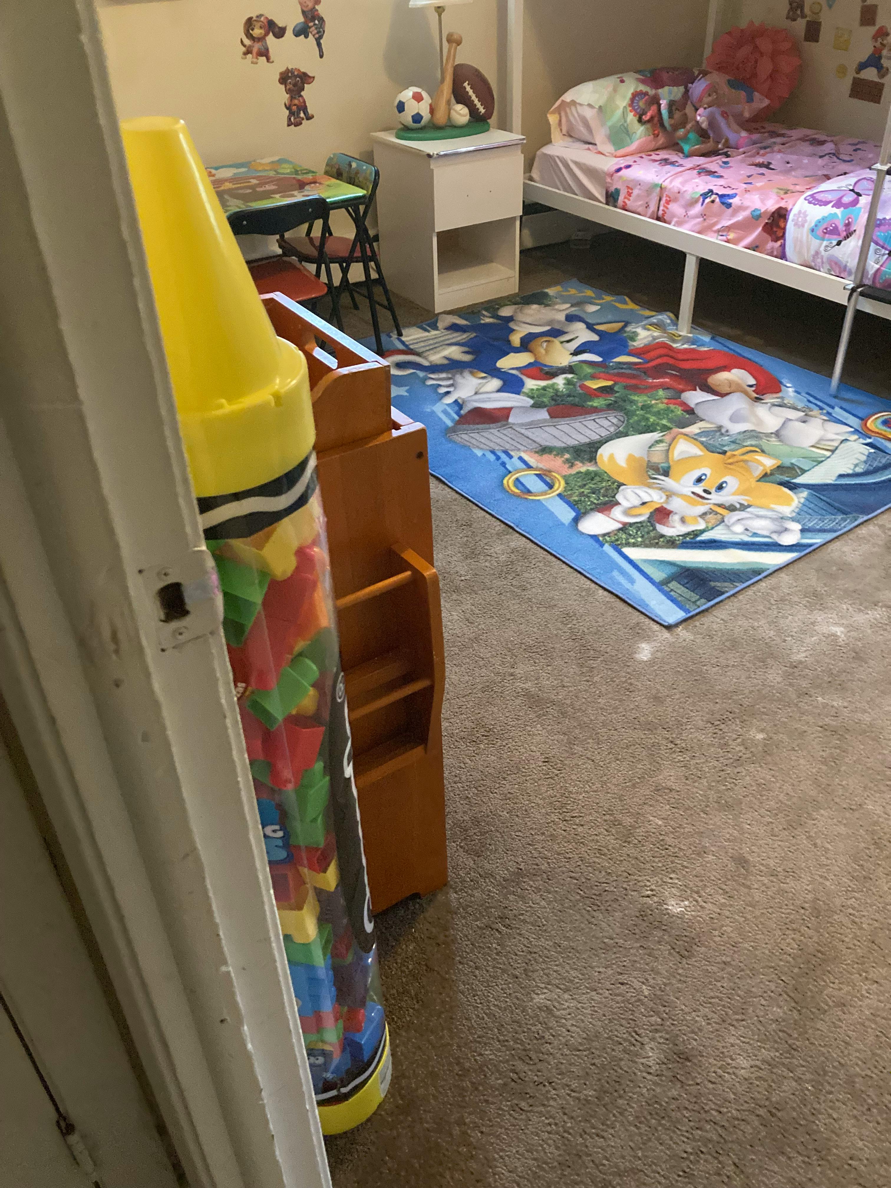 Child's bedroom with a bunk bed, Sonic the Hedgehog rug, and large crayon toy