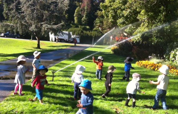 Children playing in sprinklers on a grassy lawn