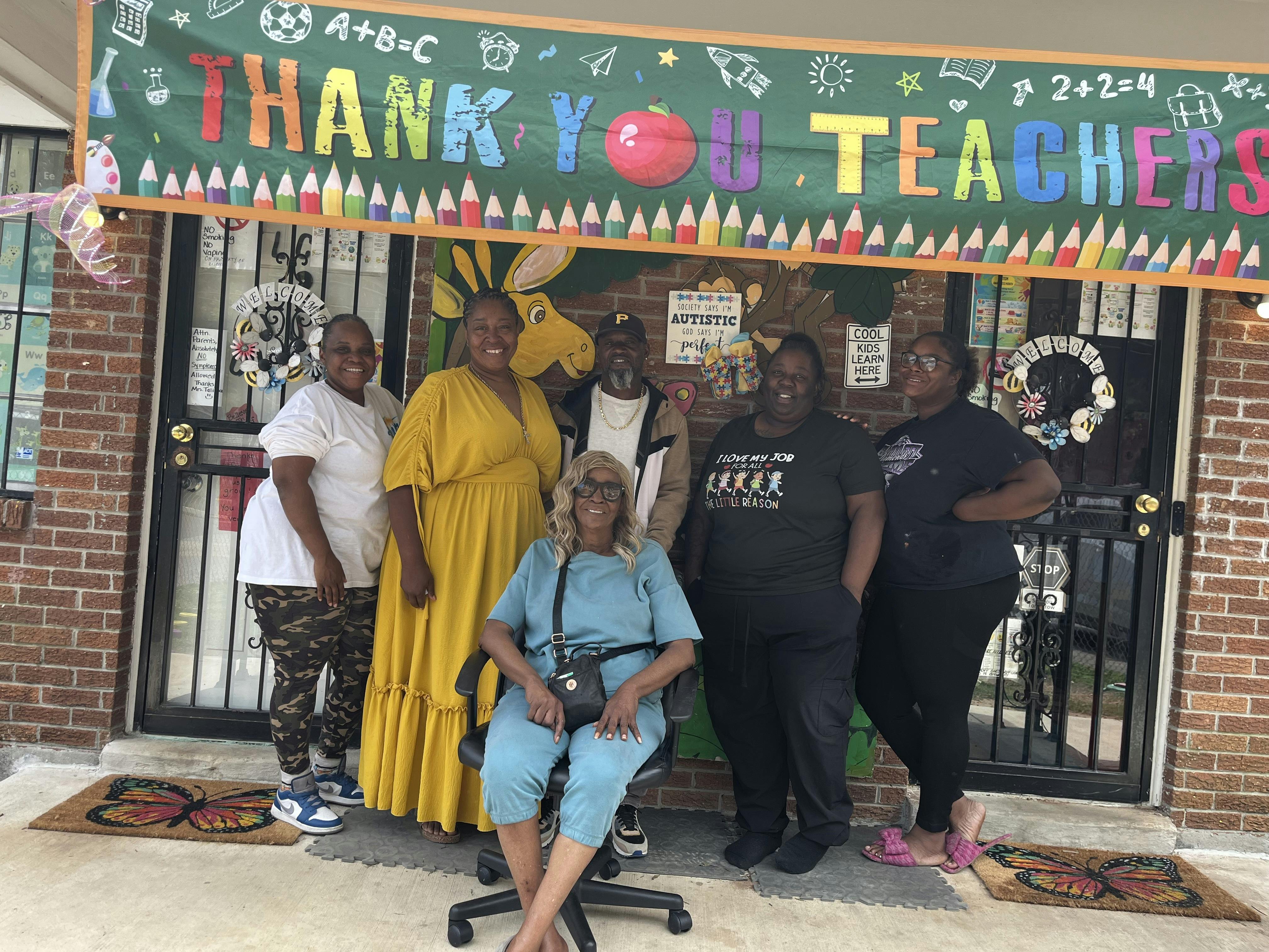 Group of six people standing in front of a Thank You Teachers banner