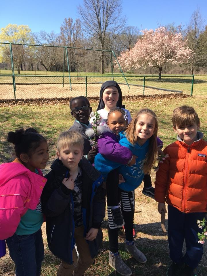 Person in black head covering with a group of children outdoors