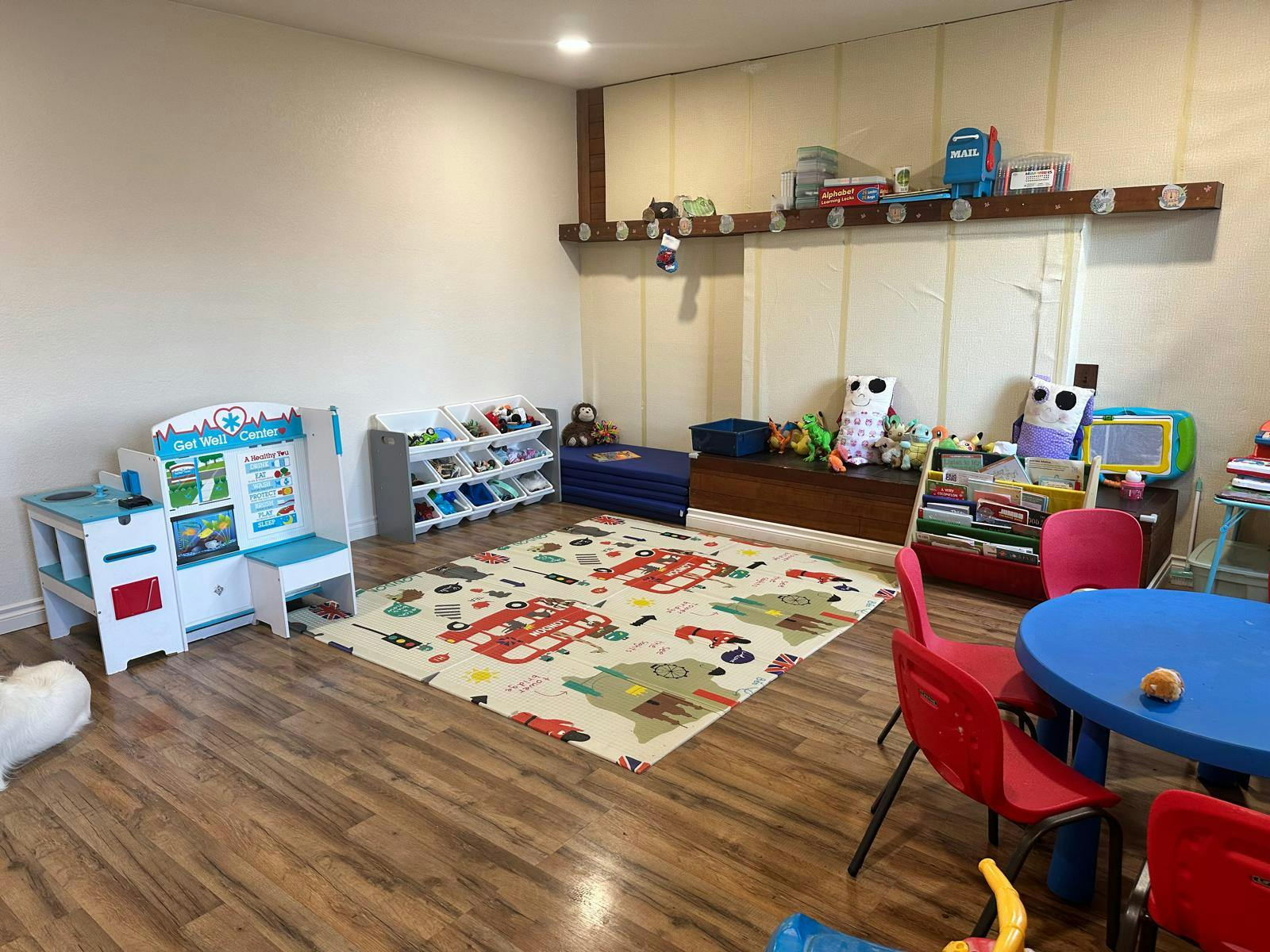 Playroom with a colorful rug, small table and chairs, and toy storage