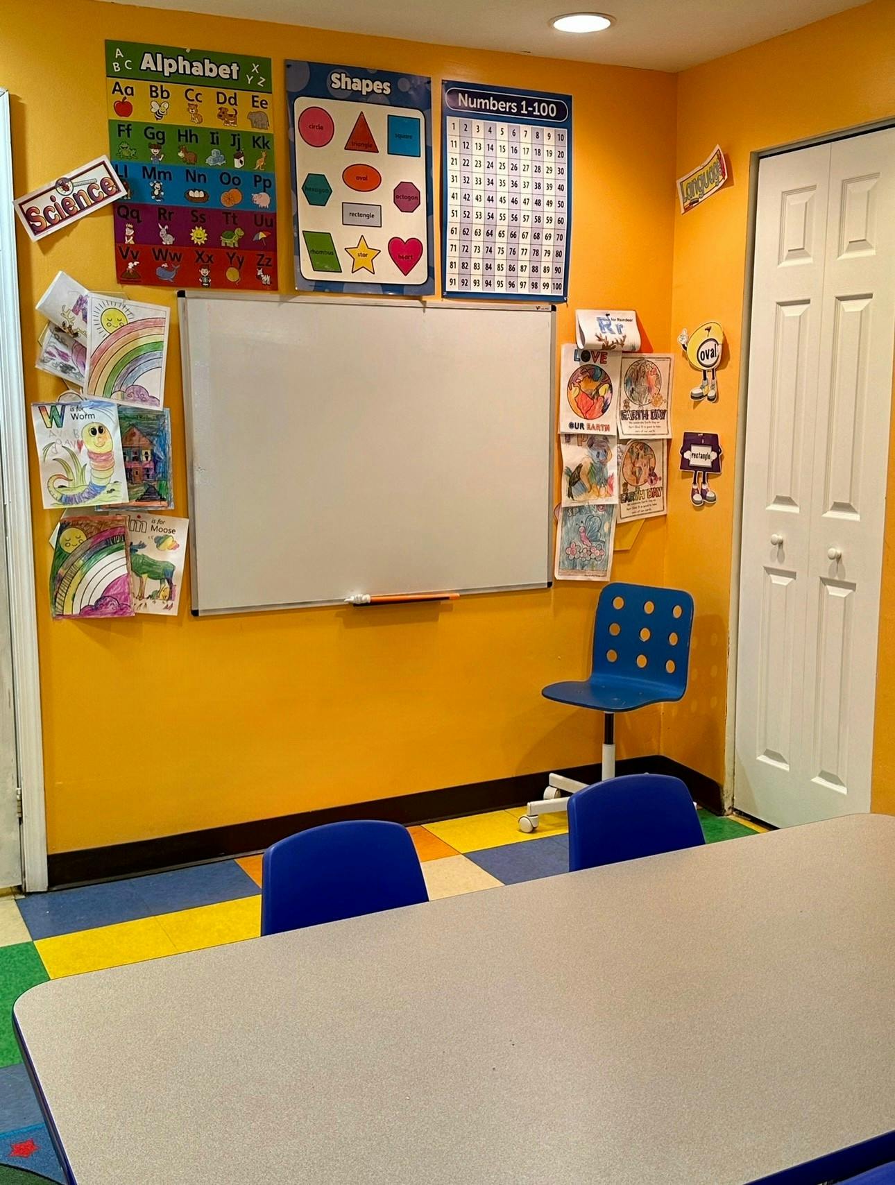 Classroom with a whiteboard, educational posters, and a table with chairs
