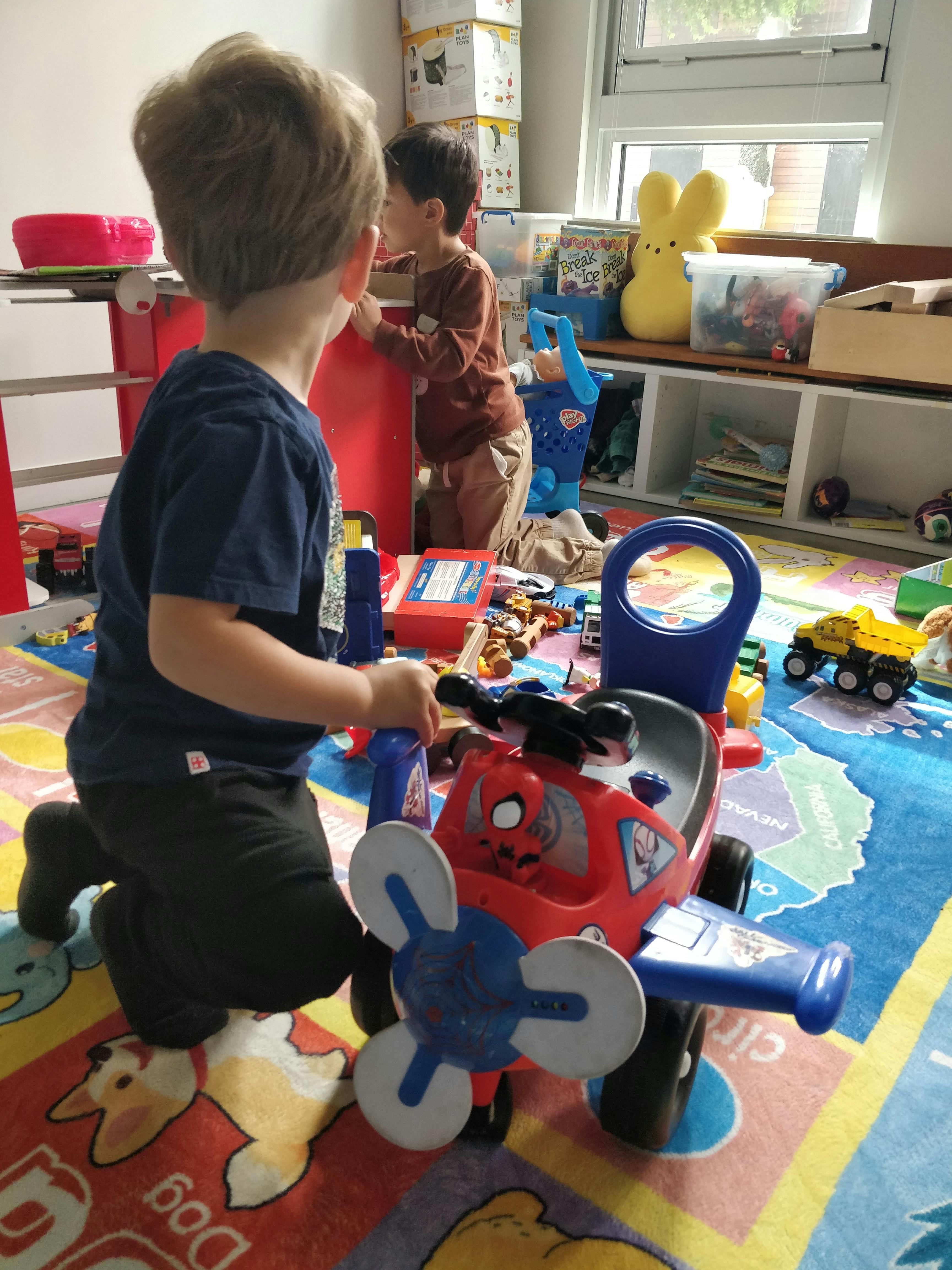 Two children playing with toys on a map-patterned rug
