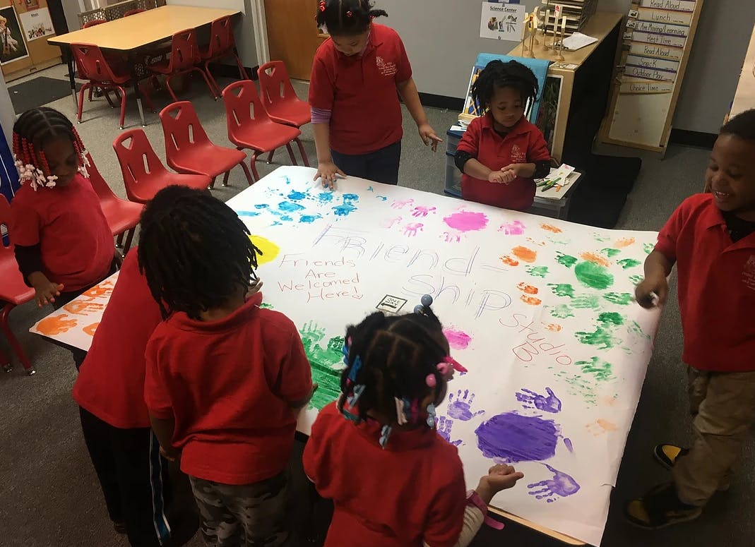 Adult and children making handprints on a large sheet of paper