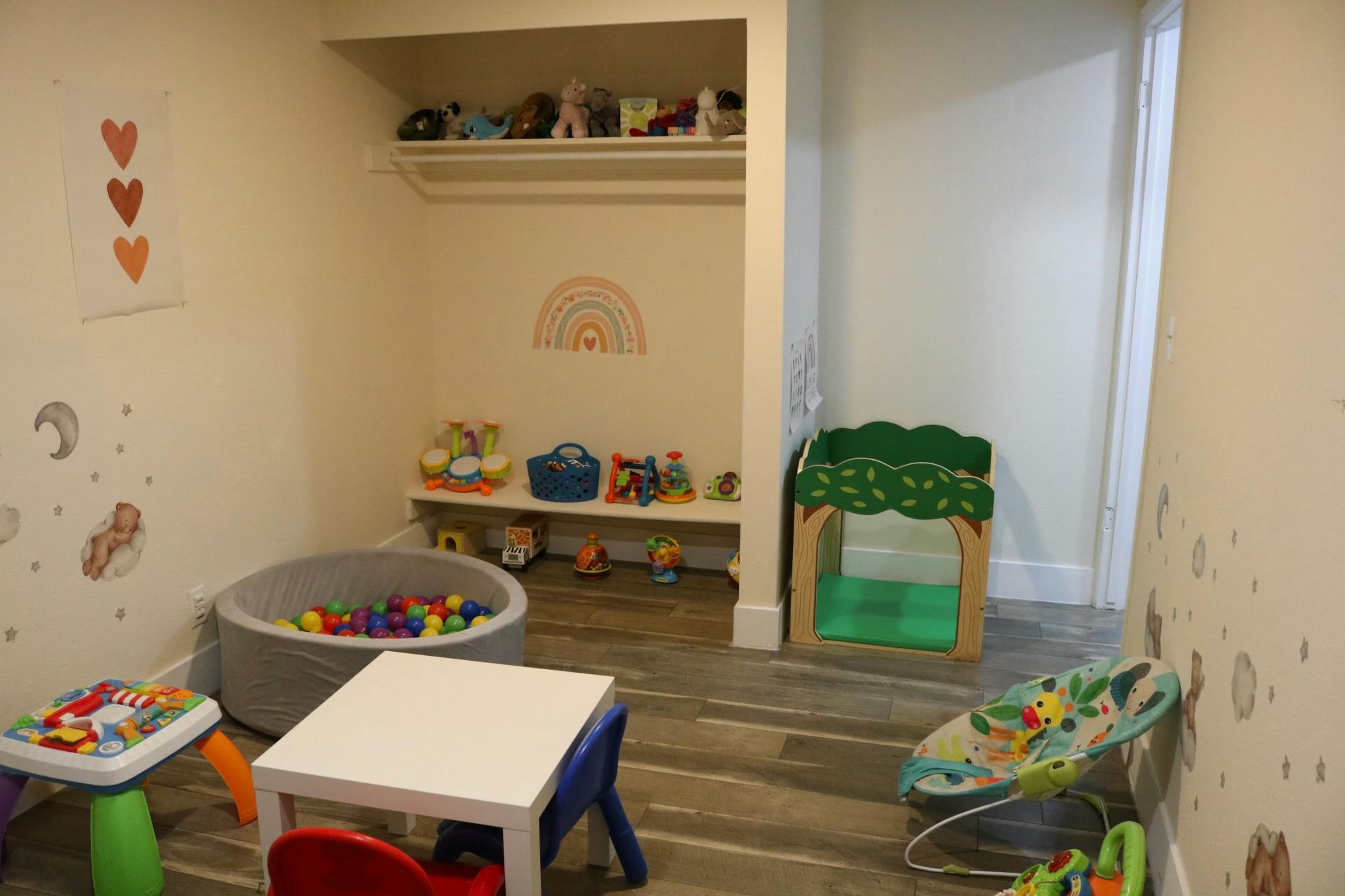 Playroom with a ball pit, small tables, and shelves of toys