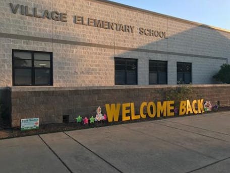 Village Elementary School building with a "Welcome Back" sign