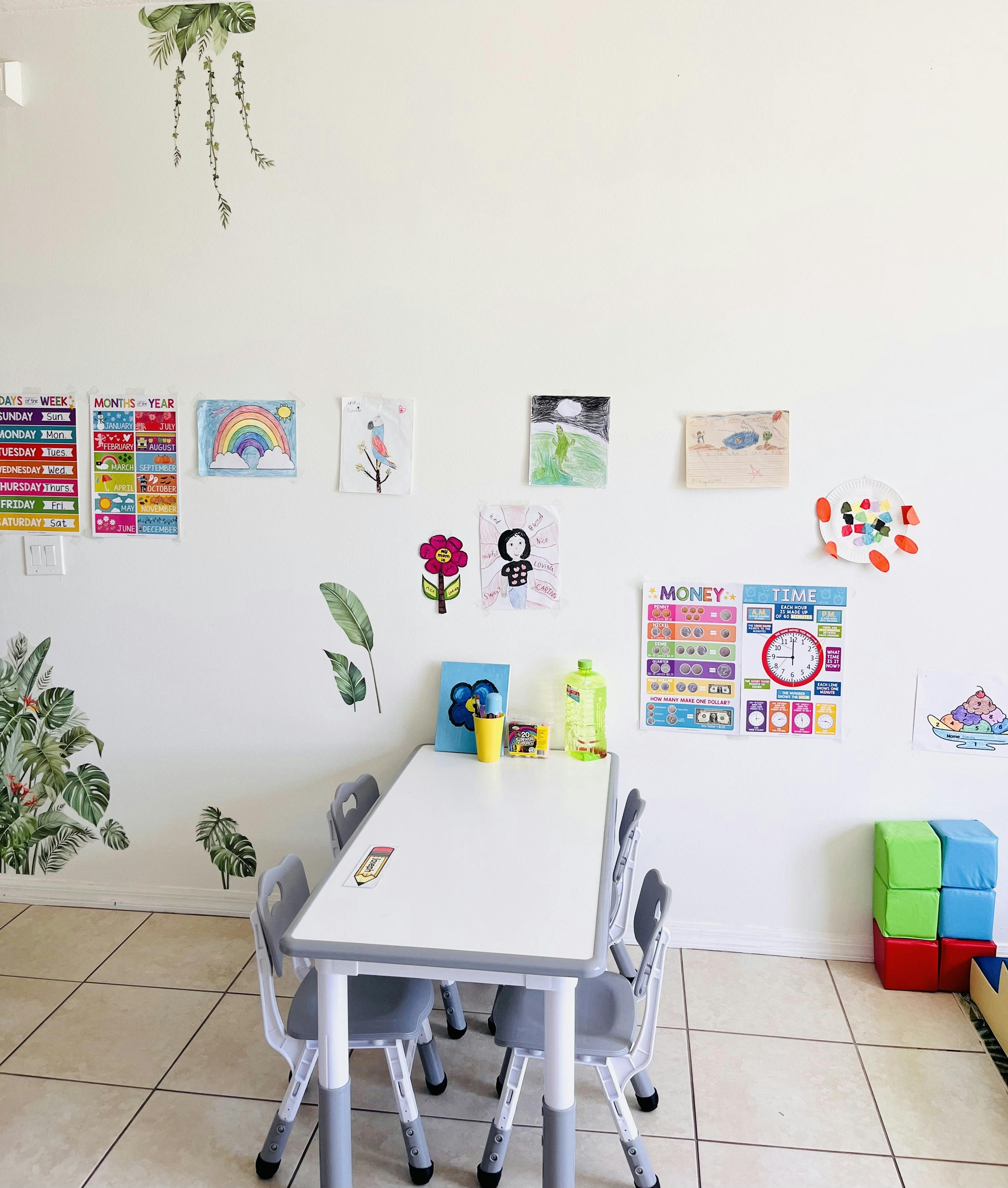 Classroom with a table, chairs, children's drawings, and educational posters