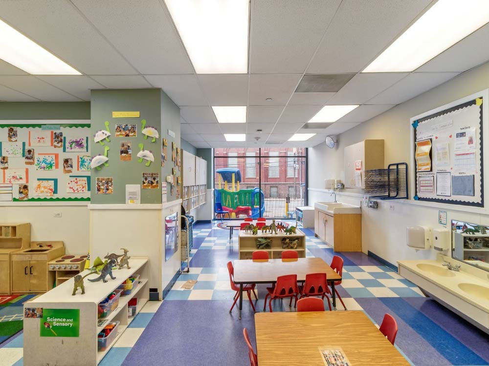 Classroom with tables, chairs, dinosaur toys, and sinks