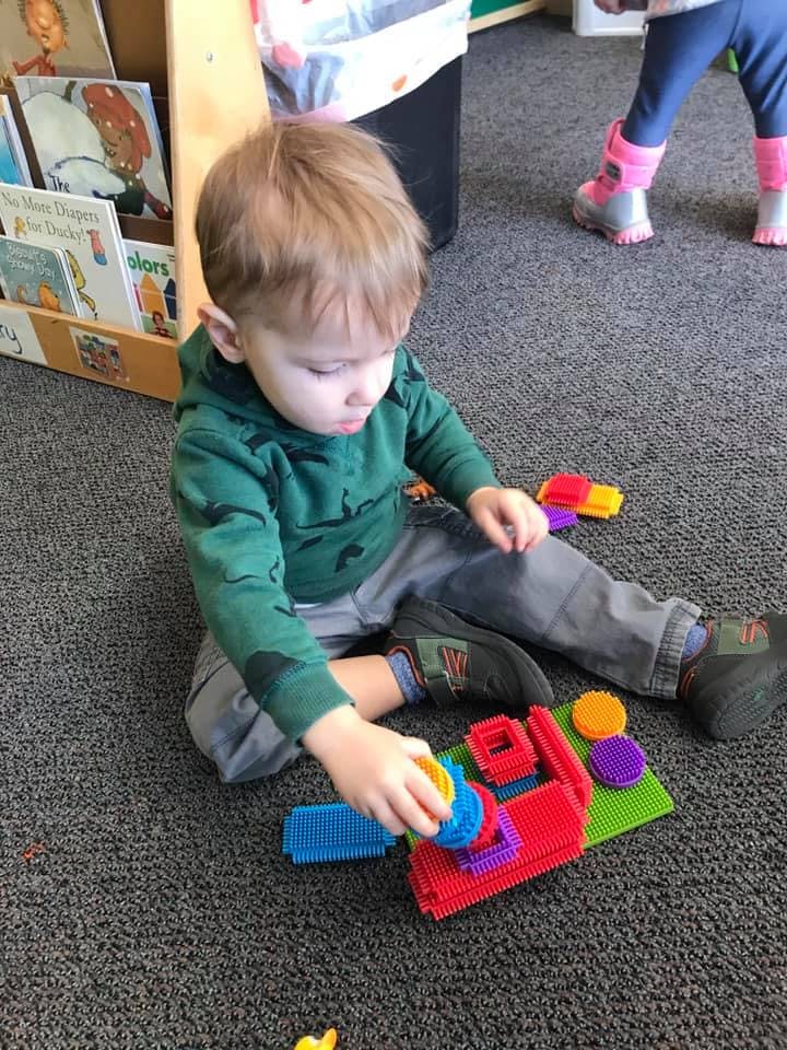 Child playing with colorful interlocking blocks on the floor