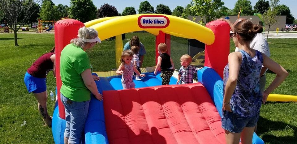 Adults and children playing on an inflatable bounce house with a slide