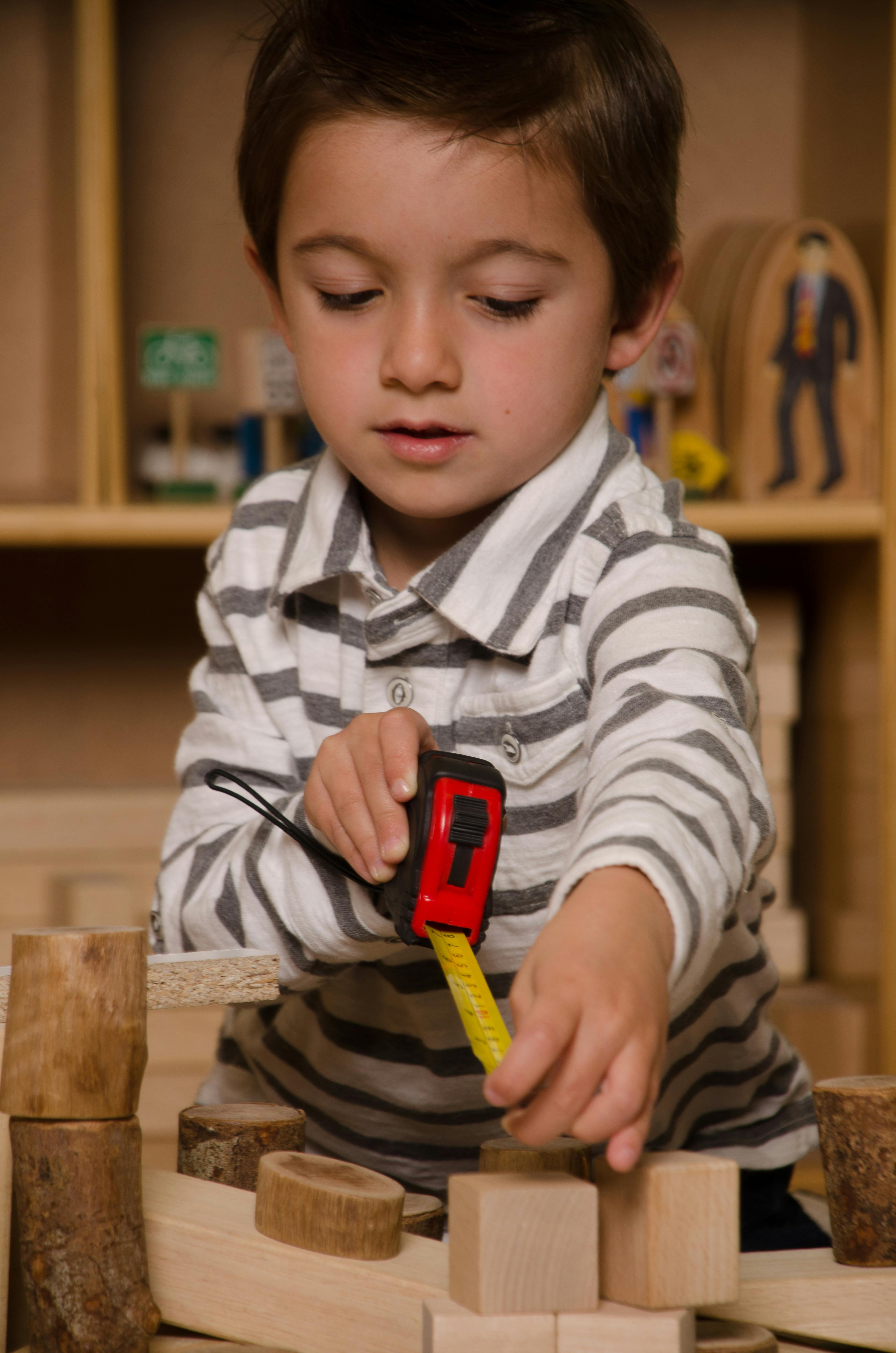 Child using a tape measure with wooden blocks