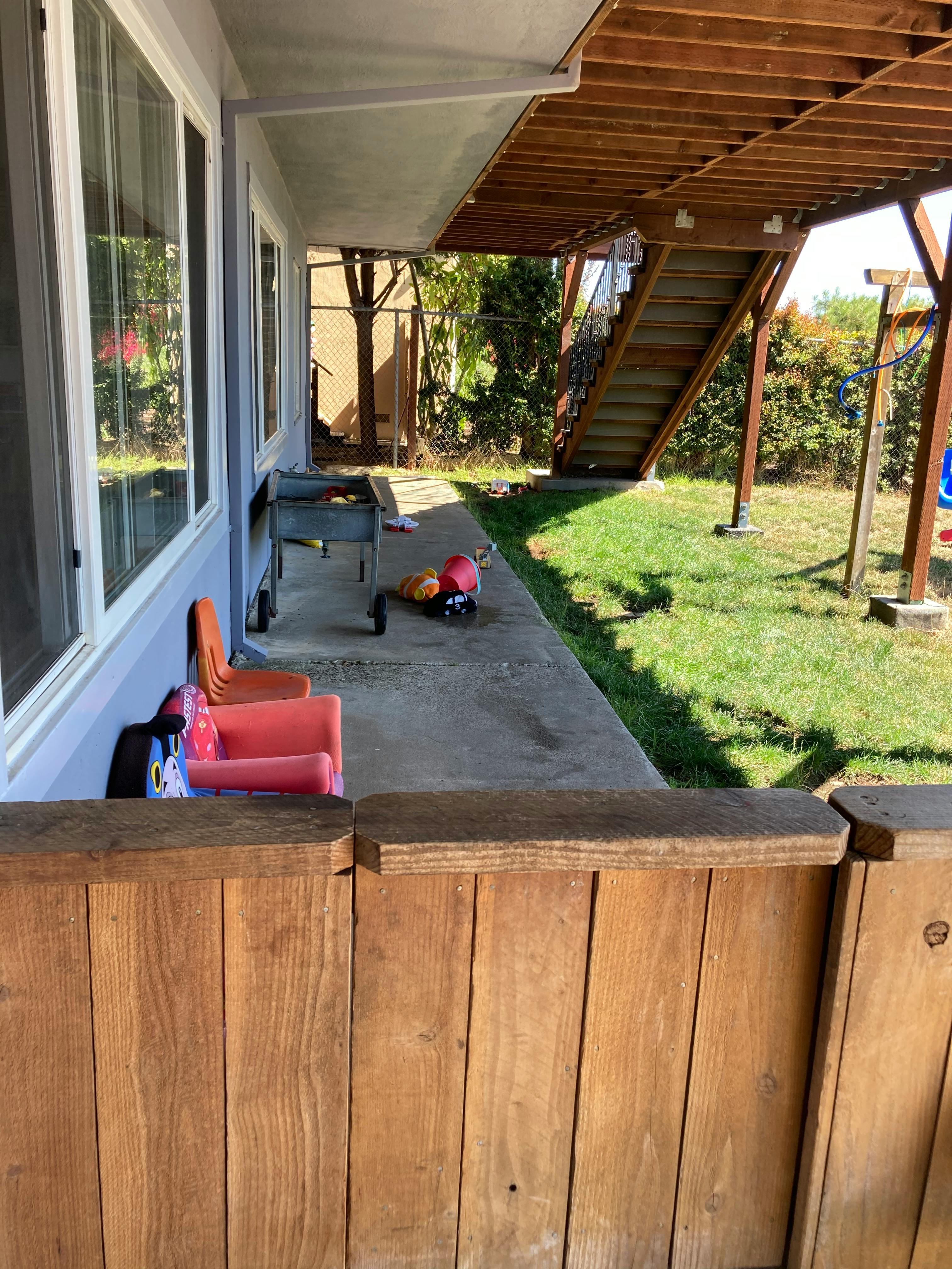 Patio with children's chairs, grill, and wooden fence
