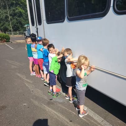 Children standing in a line next to a bus