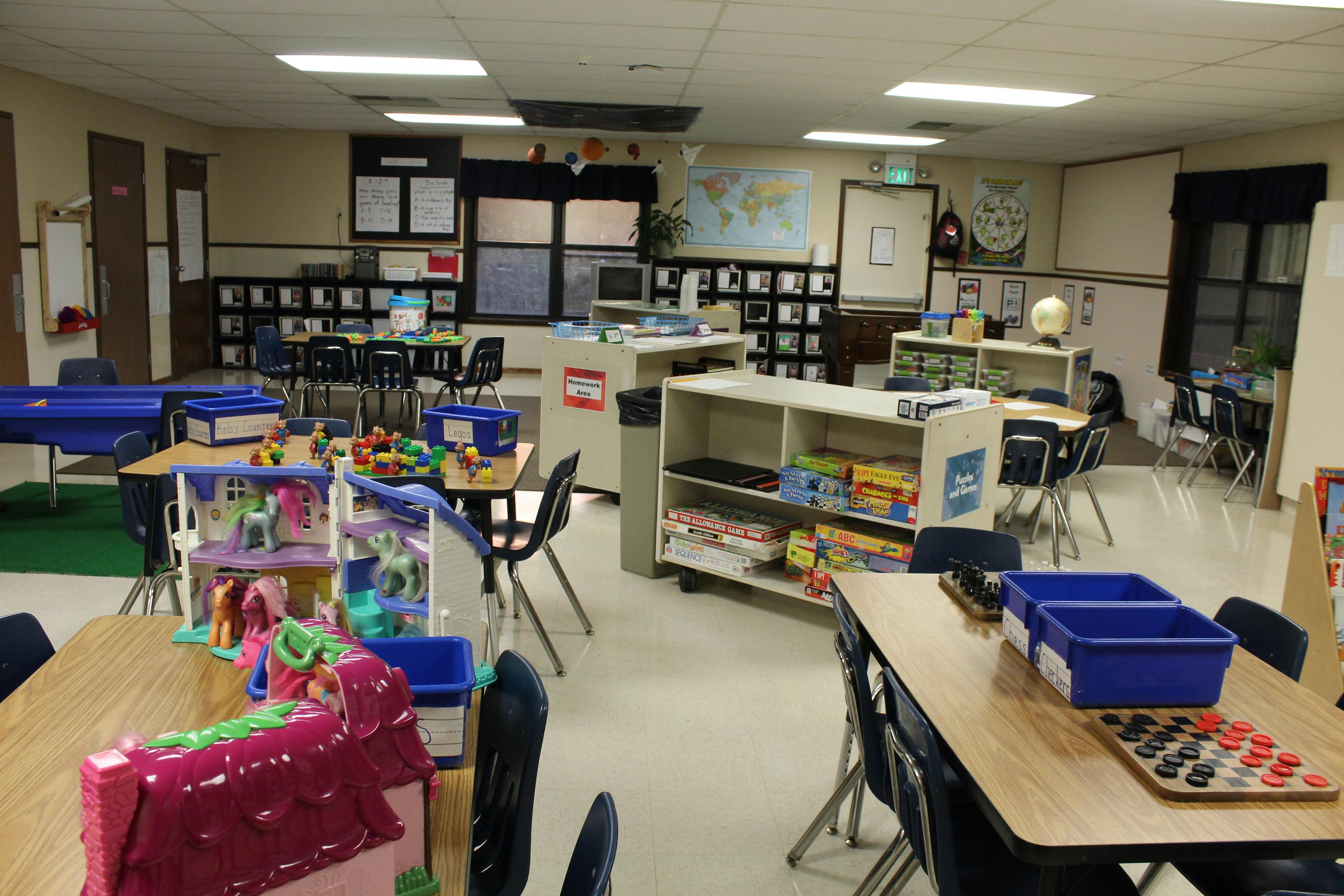 Classroom with small tables and chairs, playhouses, games, and Legos
