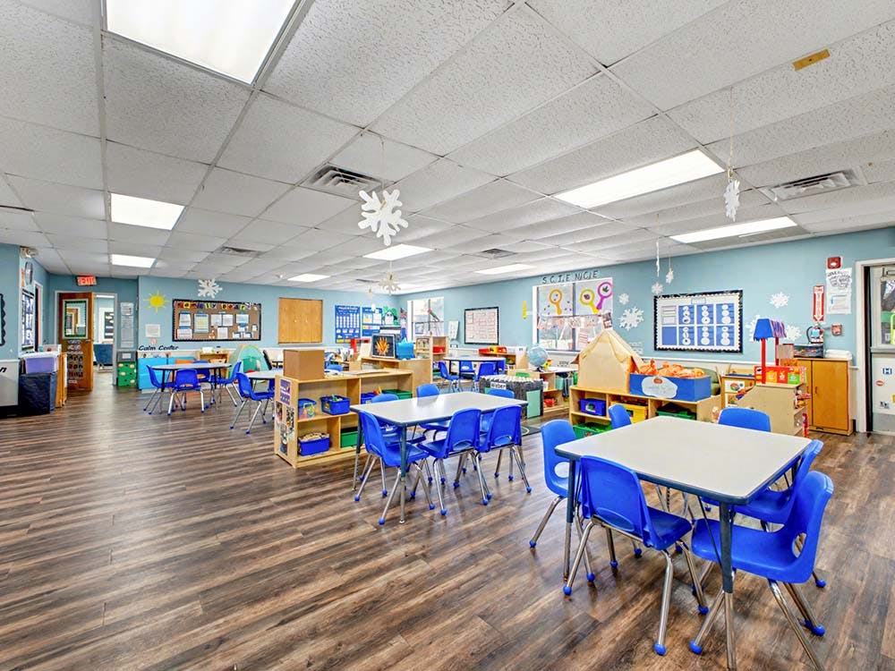 Classroom with blue chairs and light-colored tables on wooden floor