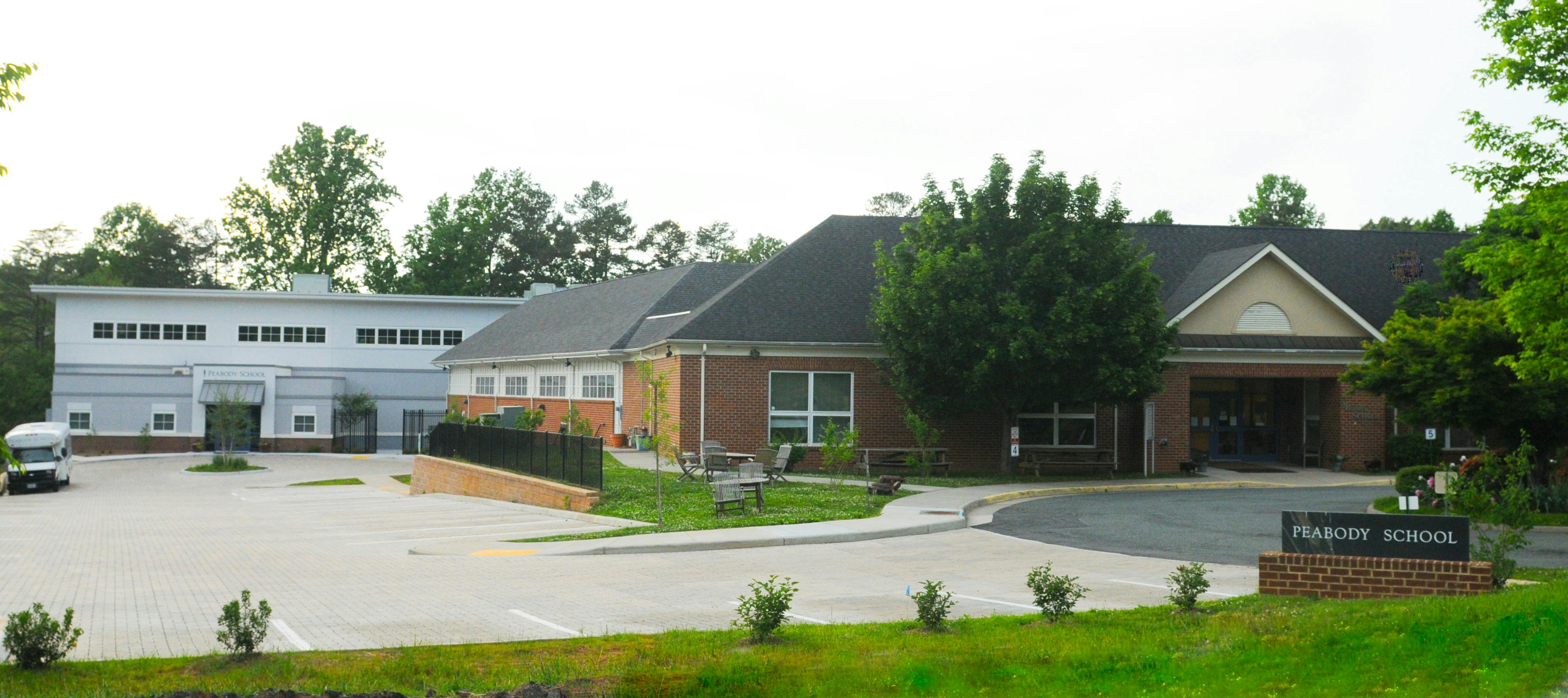 Exterior view of a school building with a parking lot and trees
