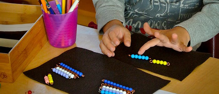 Child's hands working with colorful beaded math materials