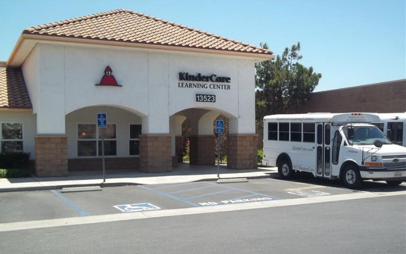 KinderCare Learning Center building with a white school bus parked