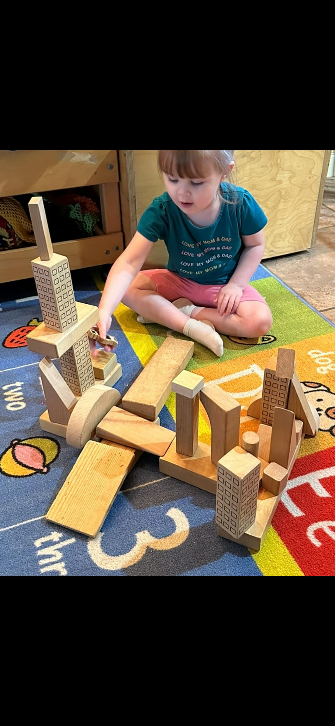 Child playing with wooden building blocks on a colorful rug