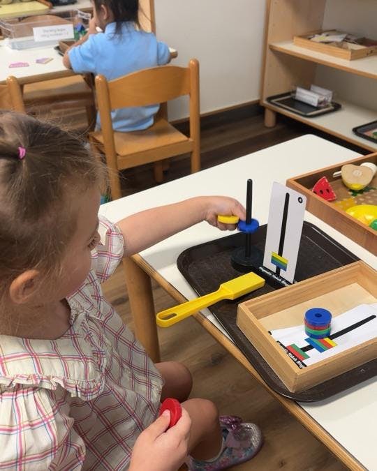 Child placing rings onto a stand in a classroom