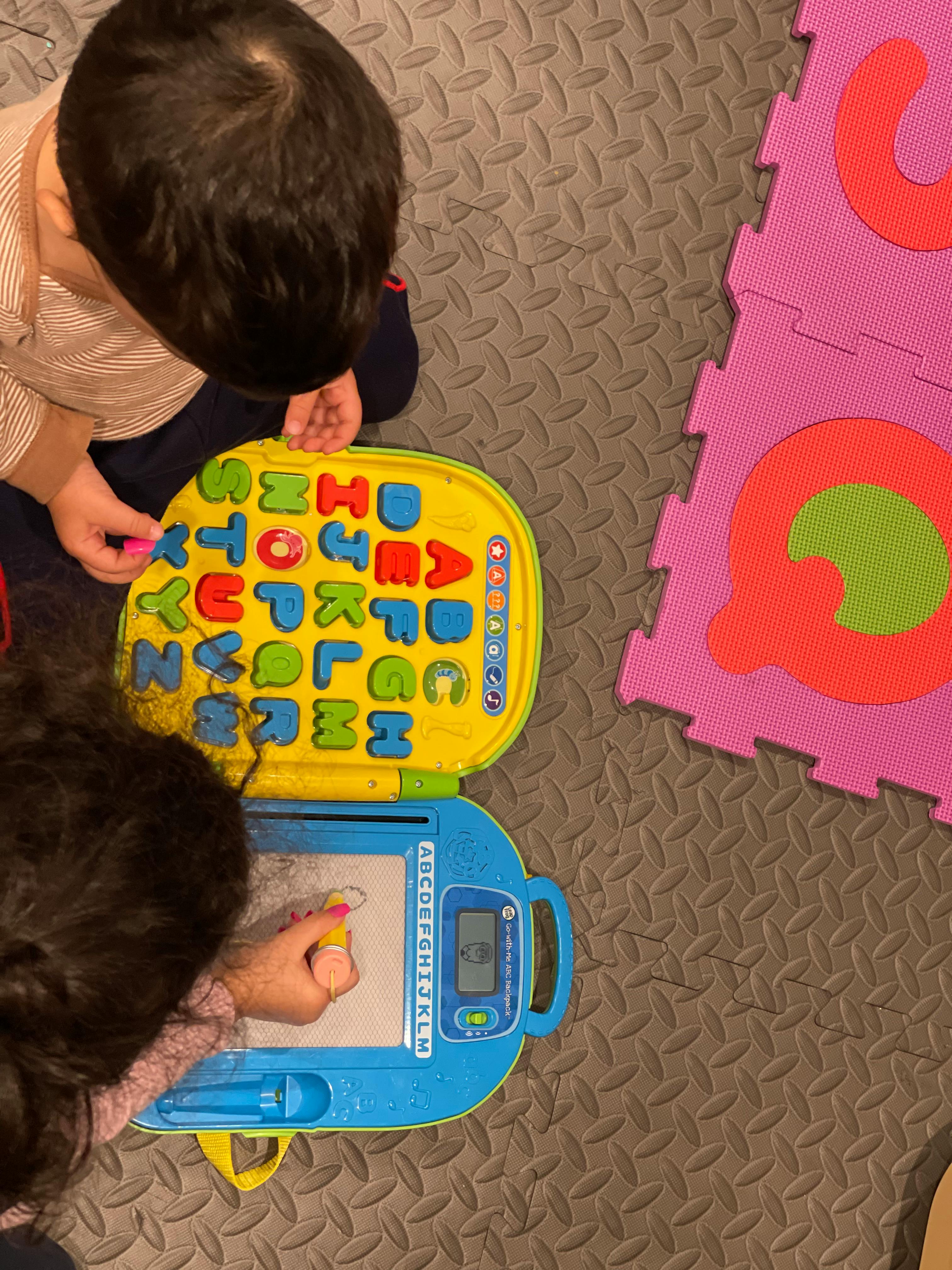 Two children playing with alphabet toys on the floor