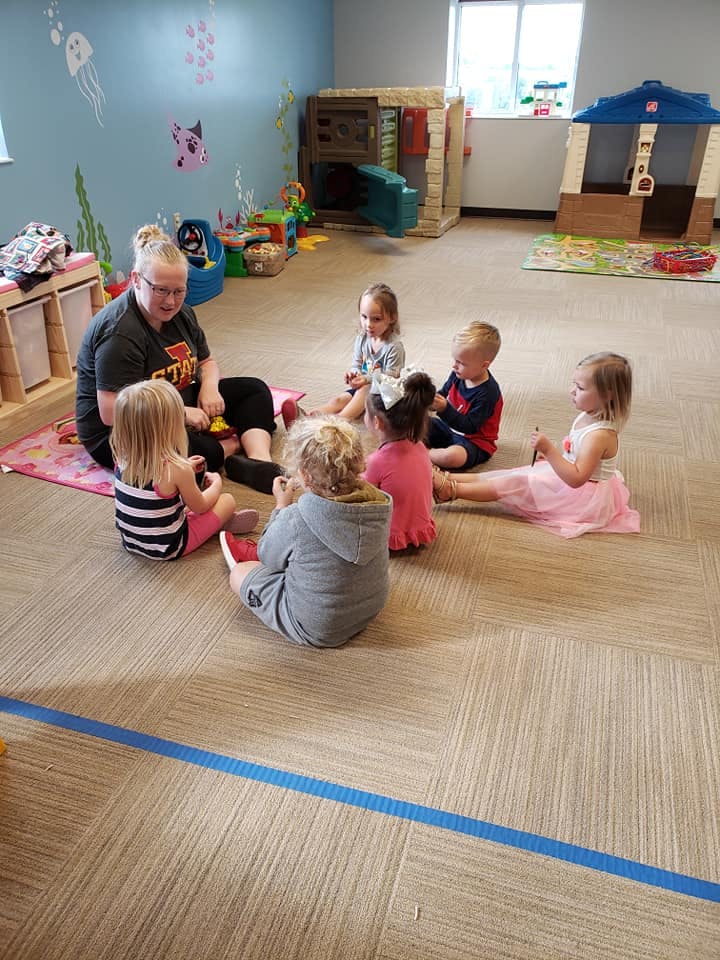Adult and children sitting on the floor in a classroom