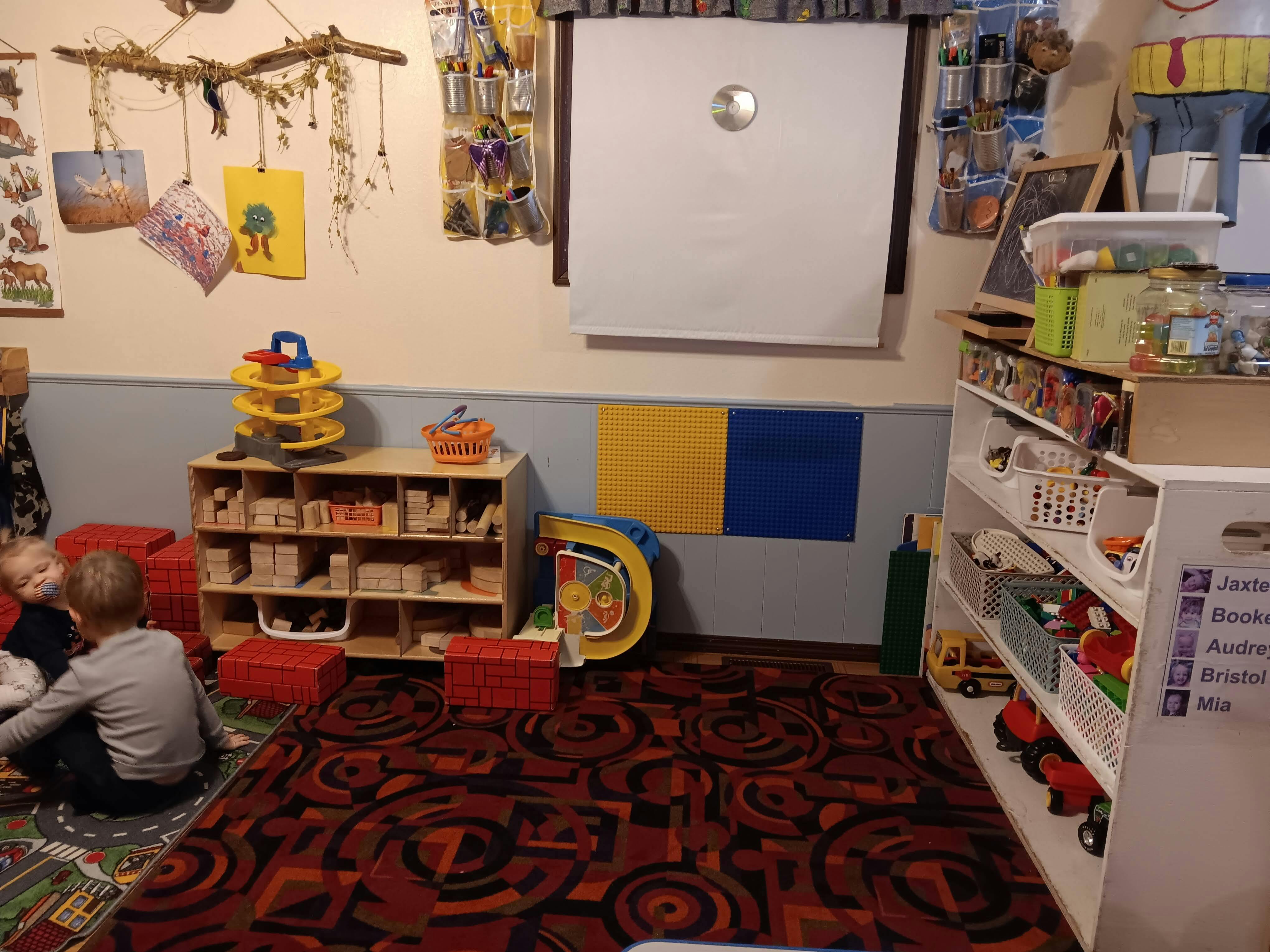 Two children sitting on a patterned rug in a playroom