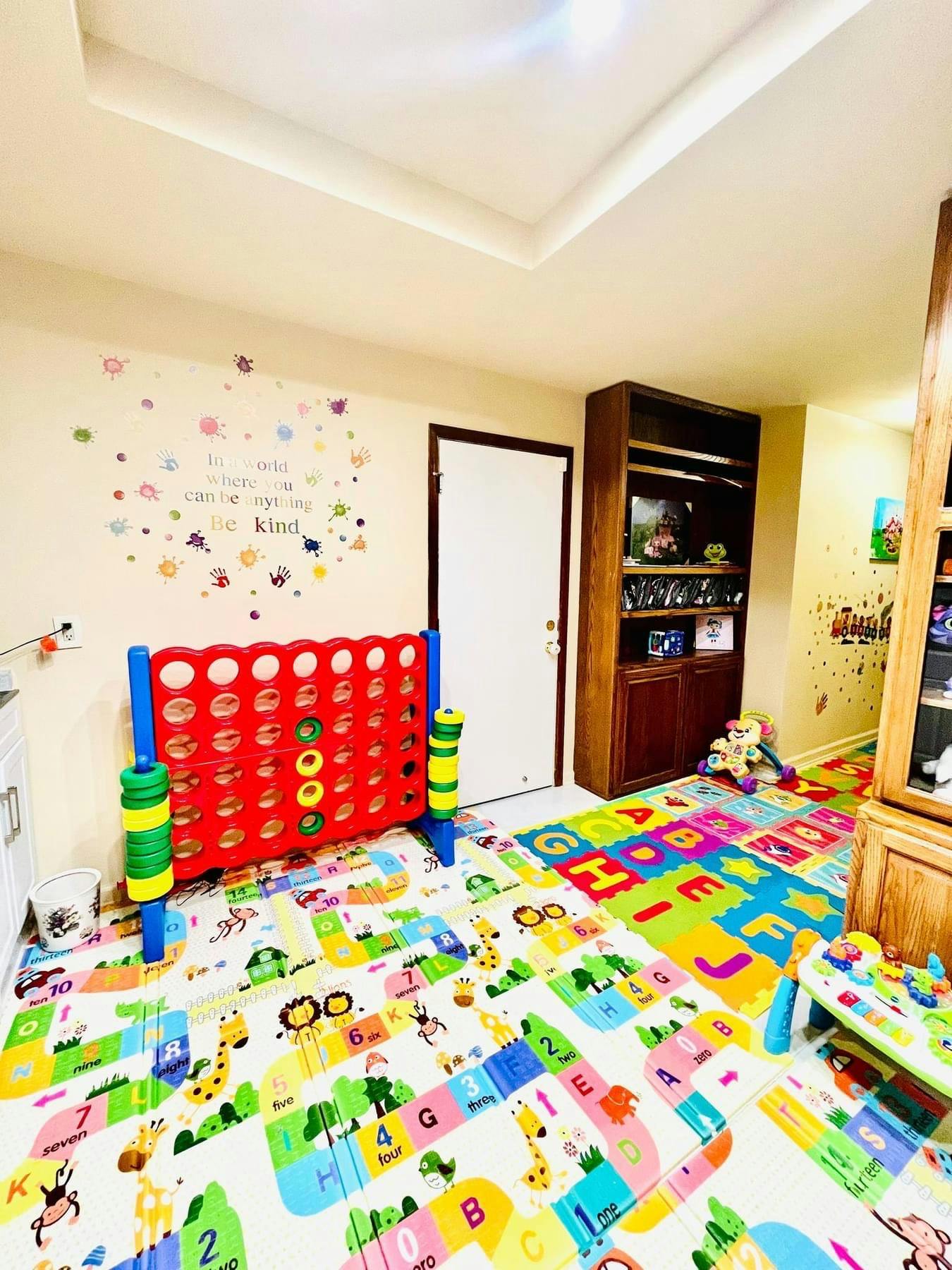 Playroom with large Connect Four game and colorful alphabet floor mats