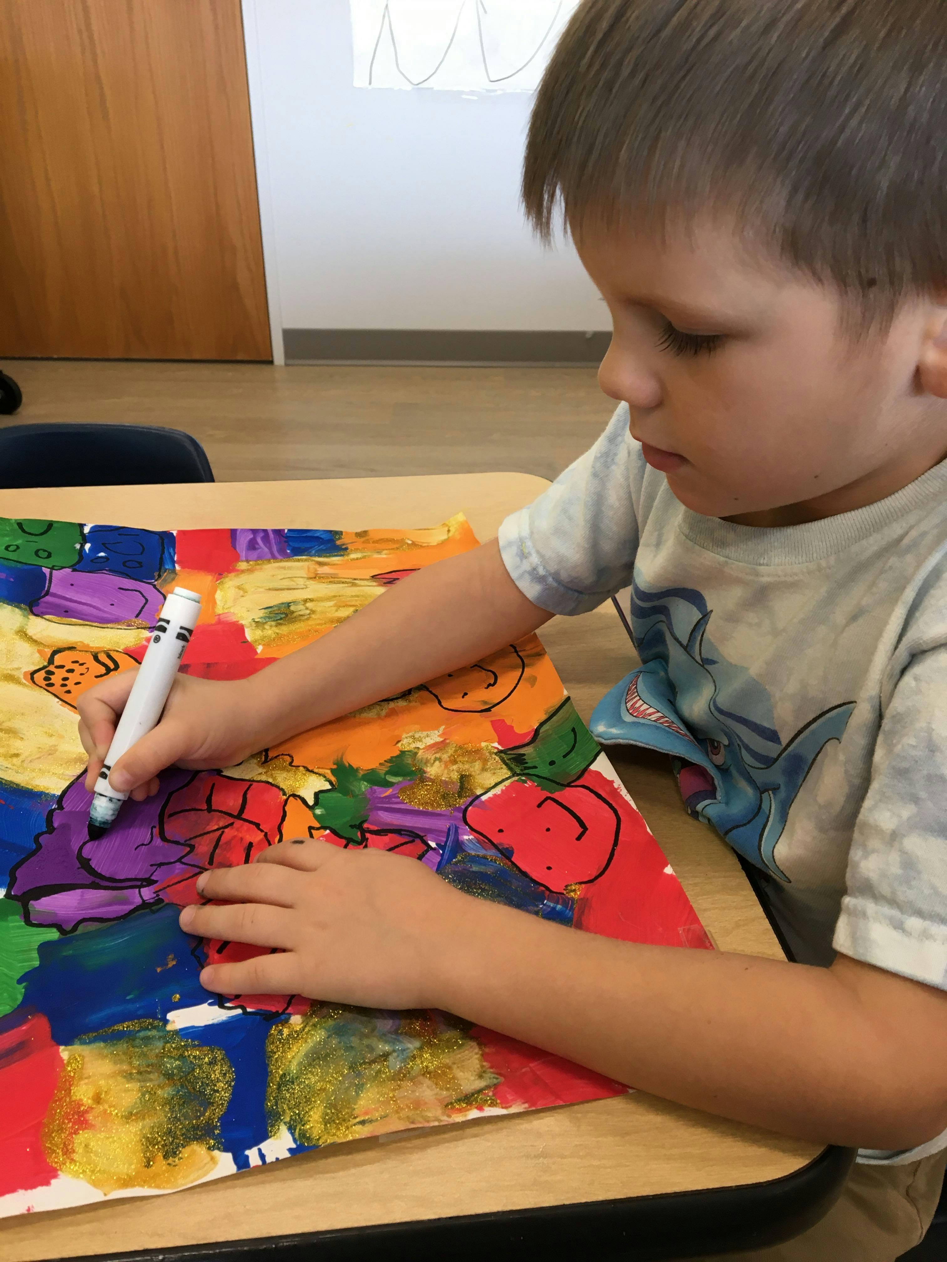 Child drawing on colorful paper with a marker