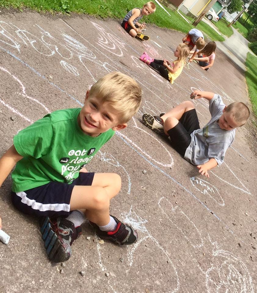 Children drawing with chalk on pavement