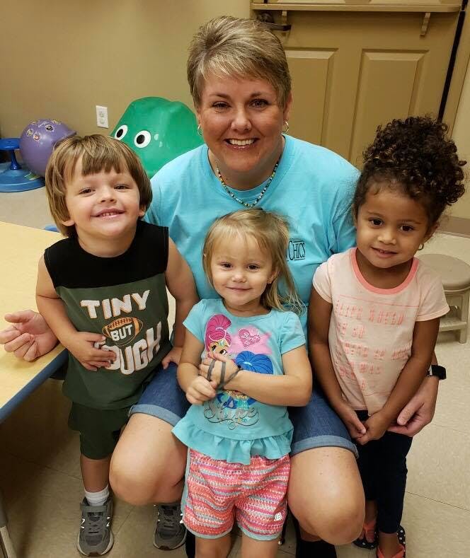 Adult person with three children in a classroom