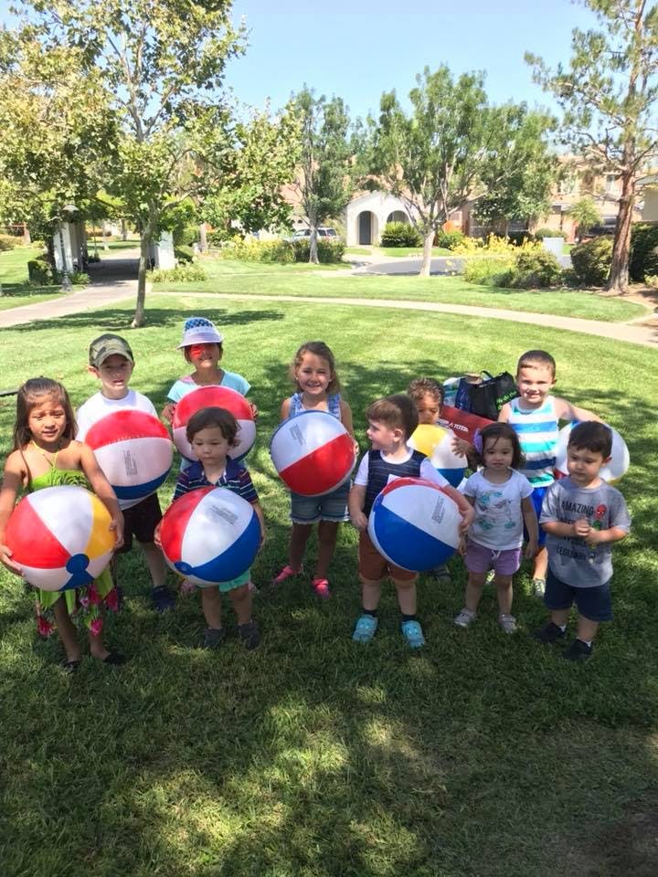 Group of children holding beach balls in a grassy park